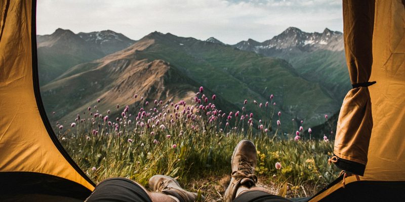 person lying inside tent and overlooking mountain